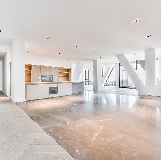Spacieux loft moderne avec cuisine épurée en bois clair, sol en marbre poli et colonnes architecturales inclinées offrant une vue panoramique.