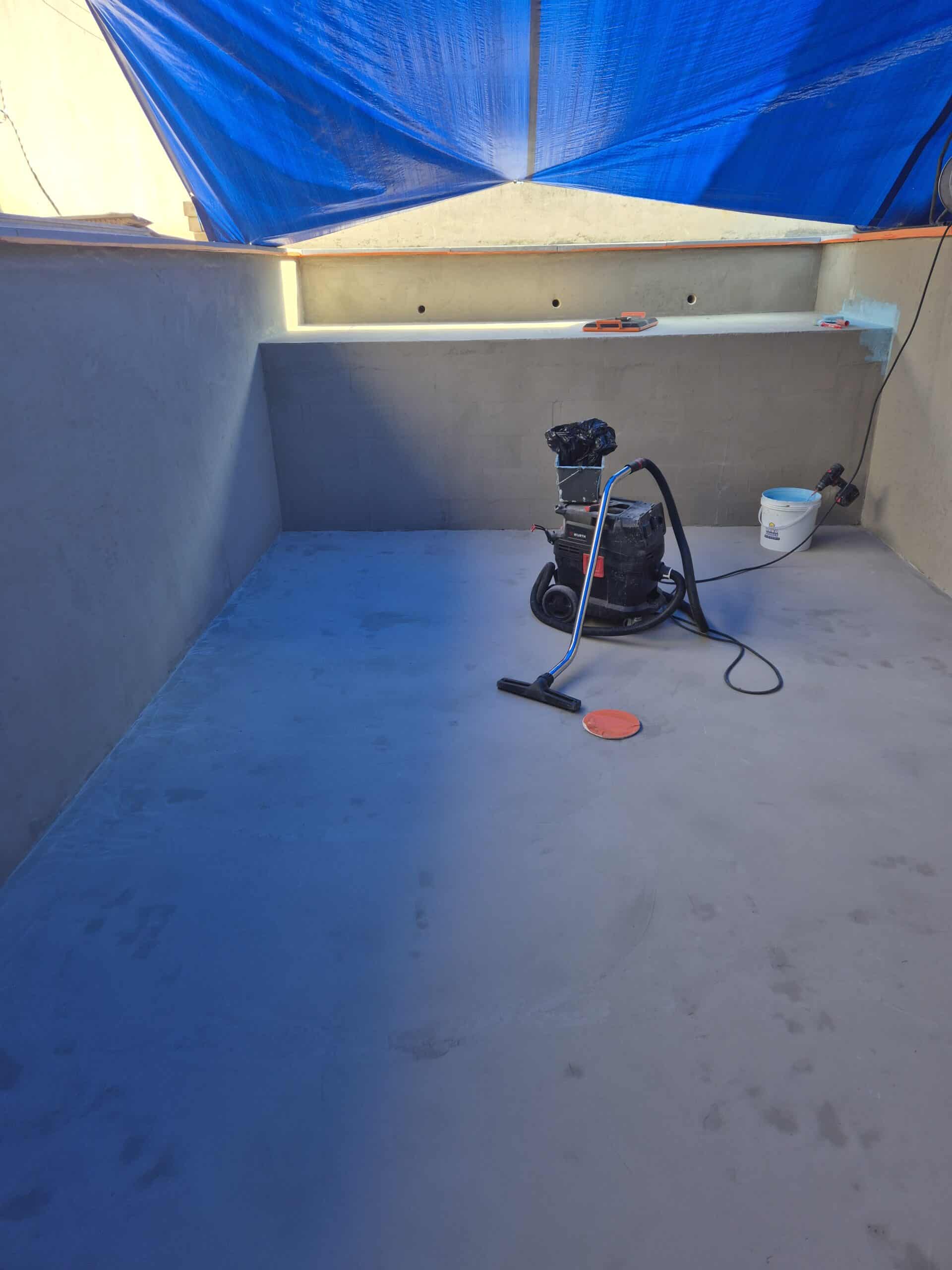 Préparation d'un bassin ou d'une piscine avec ponceuse et aspirateur Würth, sous une bâche bleue de protection.